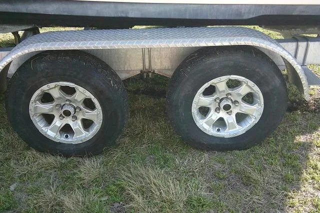 Slide: The Image of Trailer wheels for 2021 Key West 239 FS boat on grass. - 15