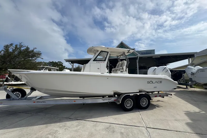 The Image of 2026 Solace 28 HCS boat on trailer, parked outdoors under a cloudy sky. - 1