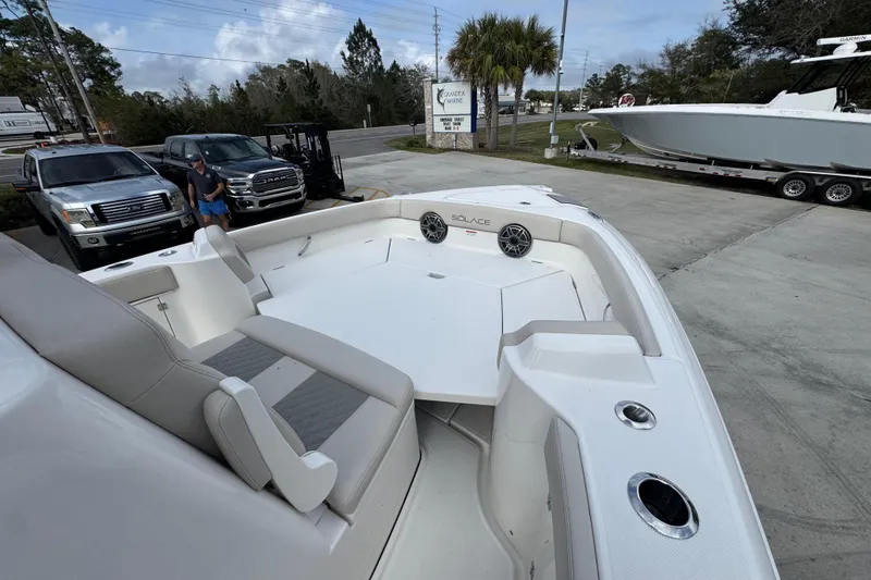 Slide: The Image of 2026 Solace 28 HCS boat with spacious seating, parked near trucks and palm trees. - 17