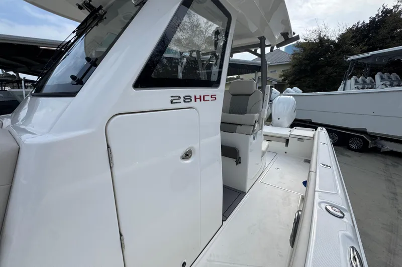 Slide: The Image of 2026 Solace 28 HCS boat, white exterior, side view, docked with seating area visible. - 22