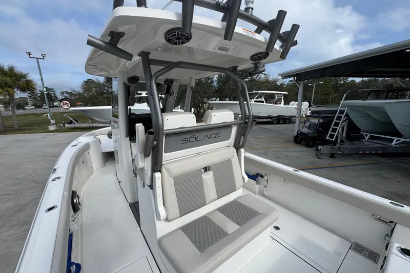 Slide: The Image of 2026 Solace 28 HCS boat interior with seating and rod holders in a marina setting. - 32