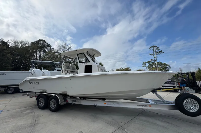 Slide: The Image of 2026 Solace 28 HCS boat on trailer, parked outdoors under a cloudy sky. - 7