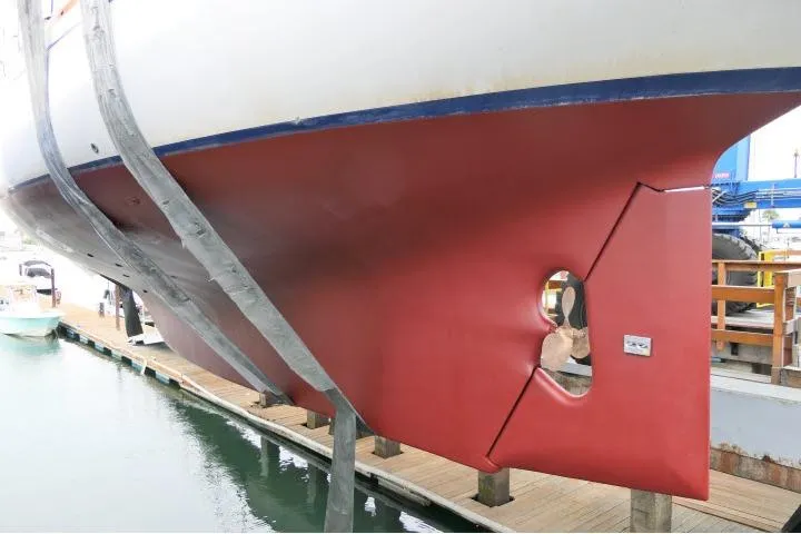 Slide: The Image of Red hull of 1982 Ta Shing Mason 63 sailboat, showcasing propeller aperture. - 100