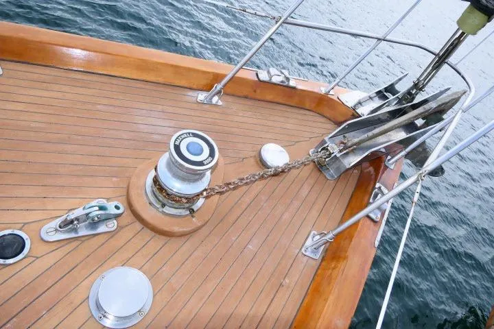 Slide: The Image of 1982 Ta Shing Mason 63 yacht deck with winch and anchor, docked on calm water. - 84