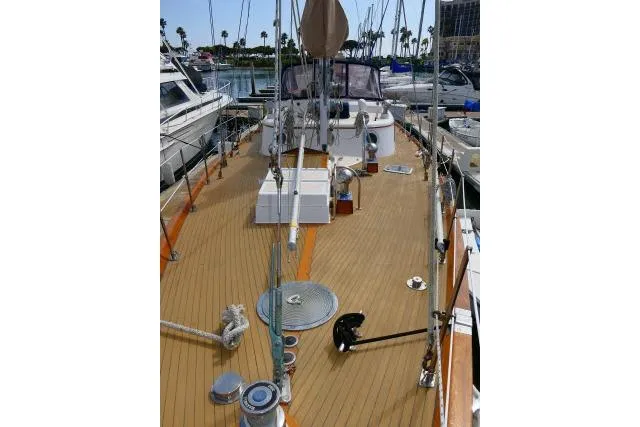Slide: The Image of 1982 Ta Shing Mason 63 sailboat deck, featuring teak wood and marina background. - 87