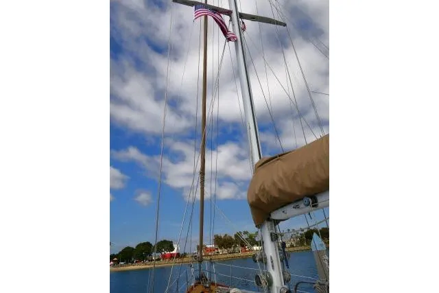 Slide: The Image of Mason 63 sailboat mast with American flag, clear sky, and palm trees in the background. - 92