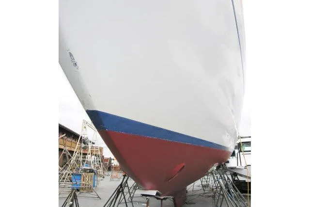 Slide: The Image of 1982 Ta Shing Mason 63 yacht hull in dry dock, showcasing red and blue paint. - 96