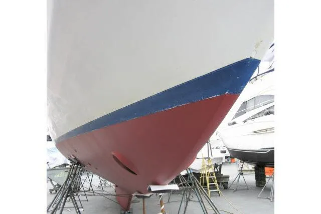 Slide: The Image of 1982 Ta Shing Mason 63 yacht hull on stands, showcasing red and blue paint. - 97