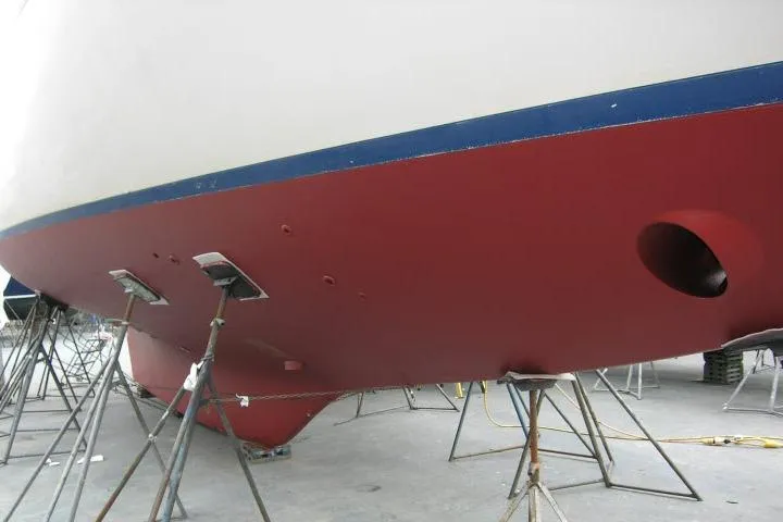 Slide: The Image of 1982 Ta Shing Mason 63 sailboat hull with visible damage, docked for repairs. - 98