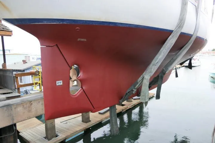 Slide: The Image of 1982 Ta Shing Mason 63 sailboat hull with visible damage, docked for repairs. - 99