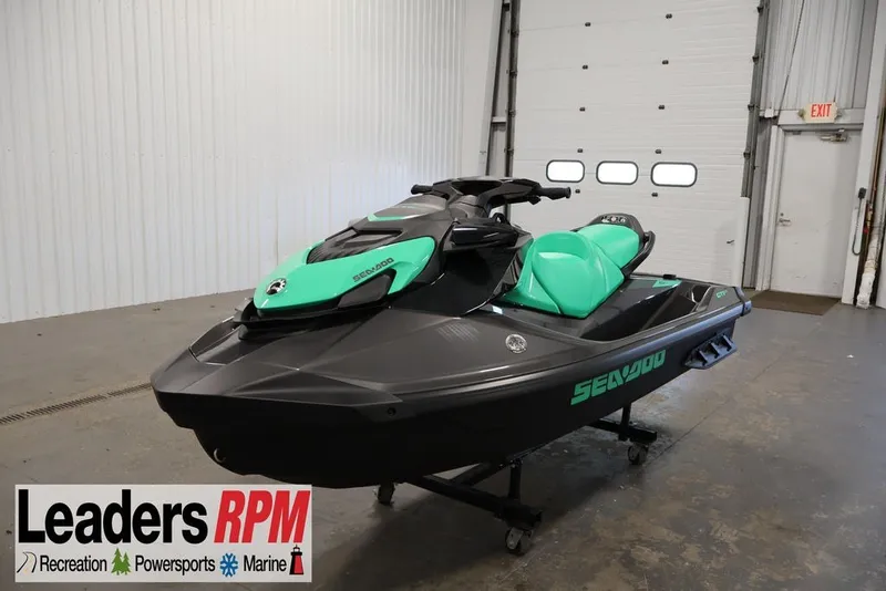 The Image of 2026 Sea-Doo GTI SE 130 jet ski in showroom, featuring sleek black and teal design. - 0