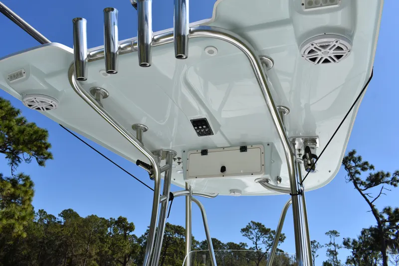 Slide: The Image of 2018 Contender 25 Bay boat T-top with rod holders and speakers against blue sky. - 27