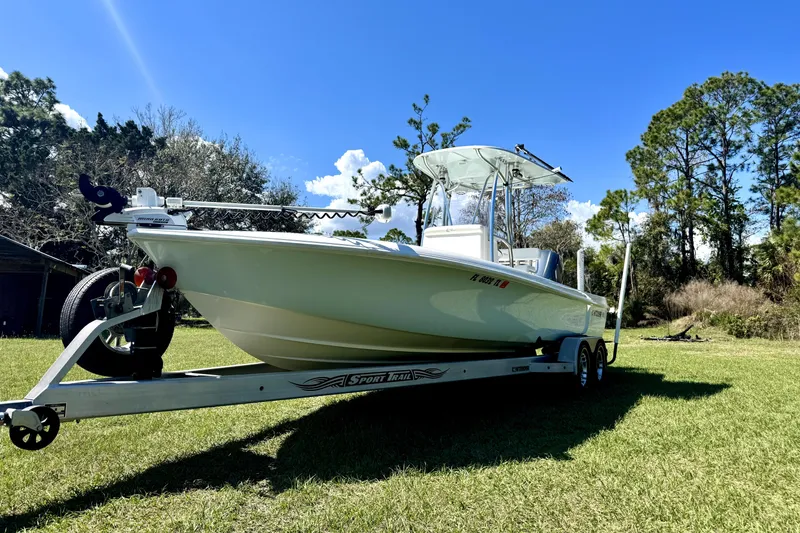 Slide: The Image of 2018 Contender 25 Bay boat on trailer, parked on grassy field under clear blue sky. - 4