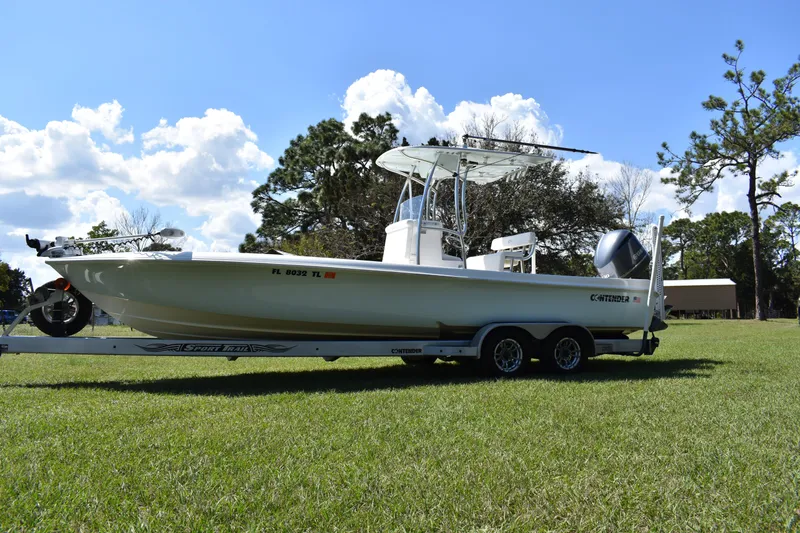 Slide: The Image of 2018 Contender 25 Bay boat on trailer, parked on grass under a blue sky. - 5