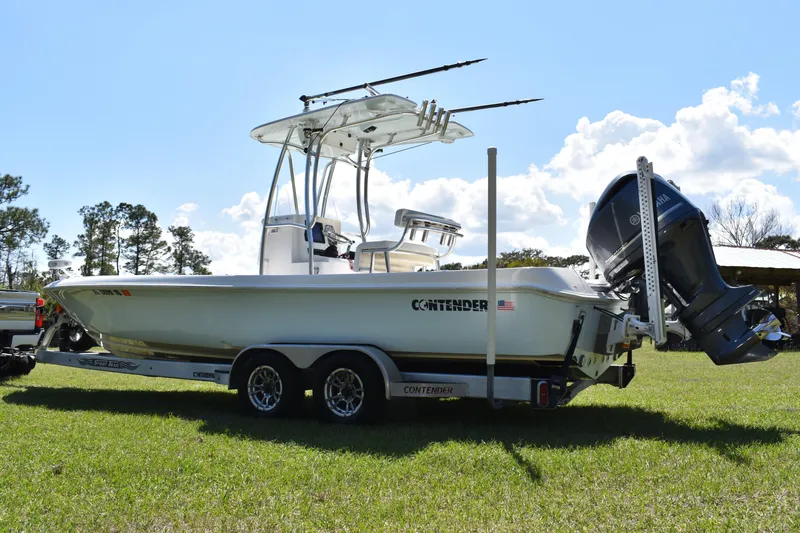 Slide: The Image of 2018 Contender 25 Bay boat on trailer, parked on grass under a clear sky. - 6