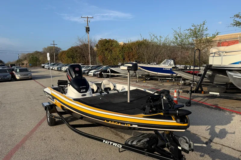 Slide: The Image of 2015 Nitro Z-6 boat on trailer in parking lot, surrounded by other boats and cars. - 2