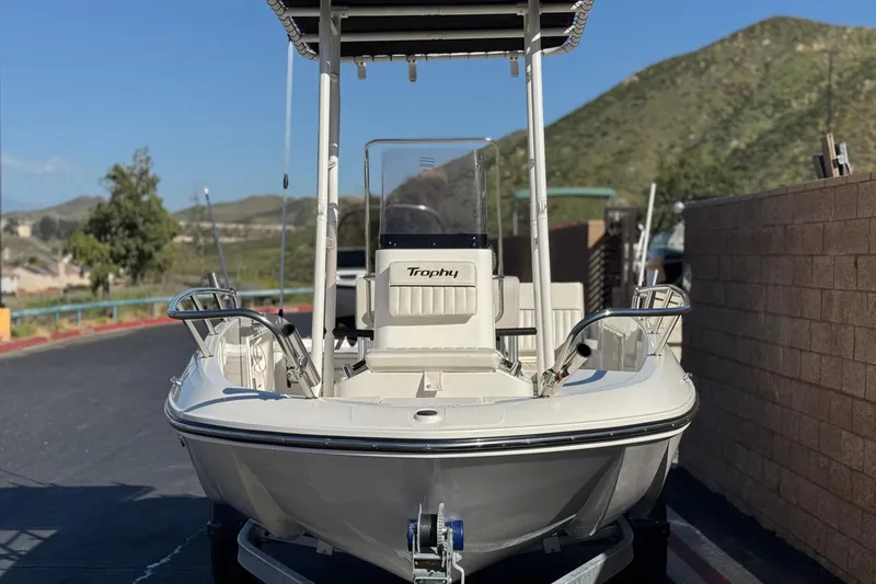 Slide: The Image of 2022 Trophy T18 boat with T-top, parked outdoors against scenic mountain backdrop. - 2