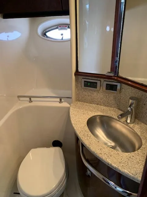 Slide: The Image of 2008 Sea Ray Sundancer bathroom with sink, toilet, and porthole window. - 26