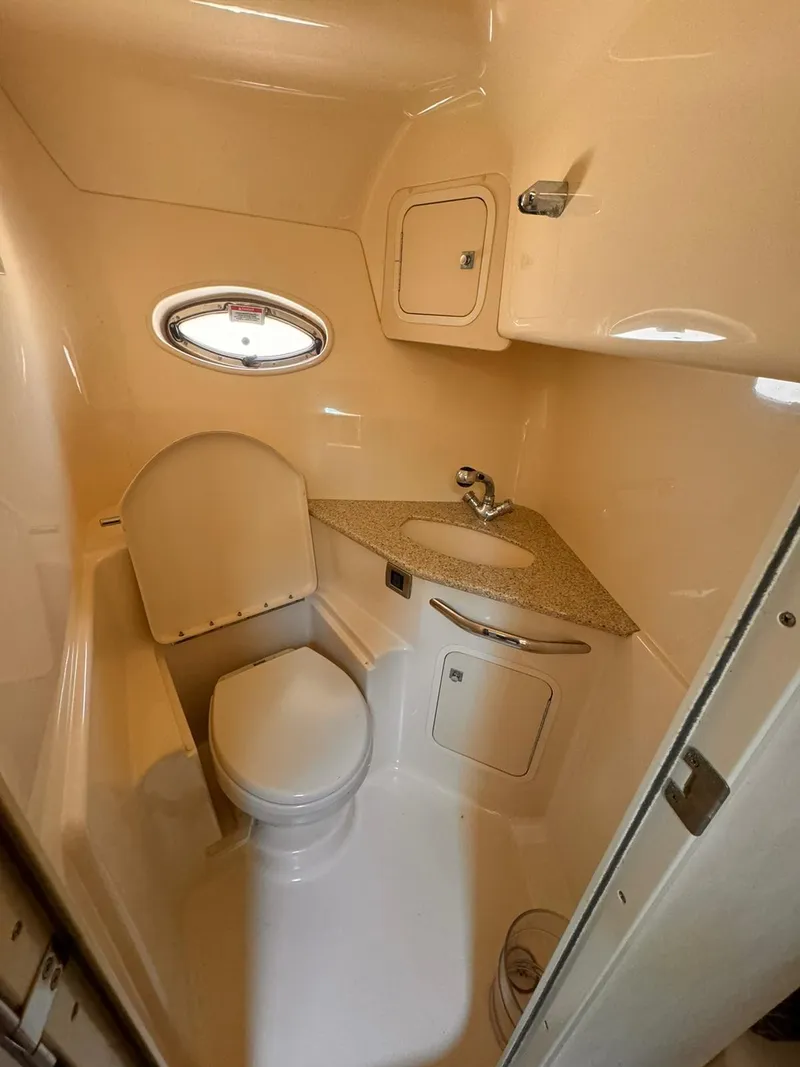 Slide: The Image of 2008 Sea Ray Sundancer bathroom with compact design, featuring a toilet, sink, and small window. - 27