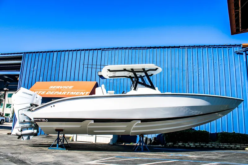 The Image of 2026 Invicta 320 CC boat displayed at service department, blue building background. - 1
