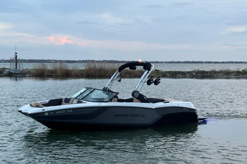 The Image of 2023 MasterCraft NXT22 boat on calm water at sunset. - 1