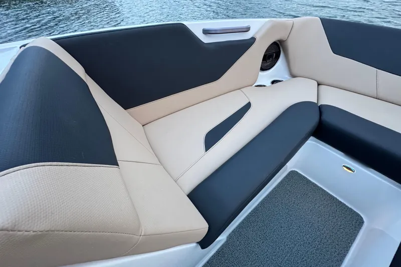 Slide: The Image of 2023 MasterCraft NXT22 boat interior with beige and black seating, near water. - 11