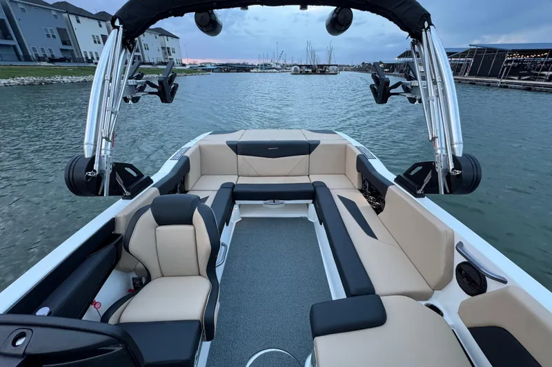 Slide: The Image of 2023 MasterCraft NXT22 boat interior with beige and black seating on a calm lake. - 13
