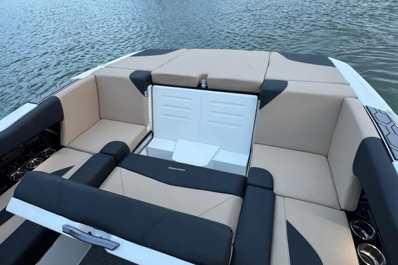 Slide: The Image of 2023 MasterCraft NXT22 boat interior with beige and black seating on water. - 23