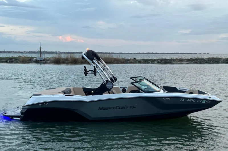Slide: The Image of 2023 MasterCraft NXT22 boat on calm water at sunset. - 4