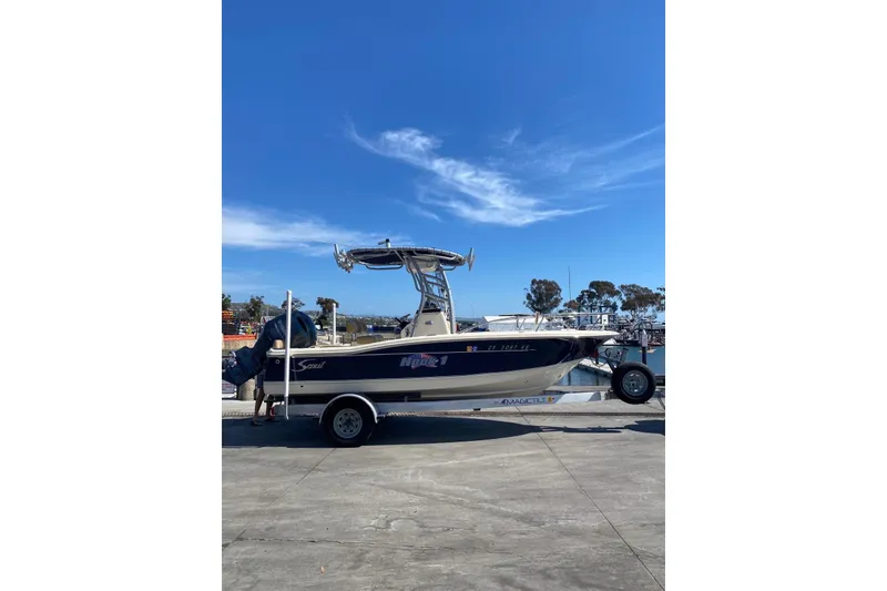 Slide: The Image of 2020 Scout 195 Sportfish boat on trailer under clear blue sky at marina. - 10