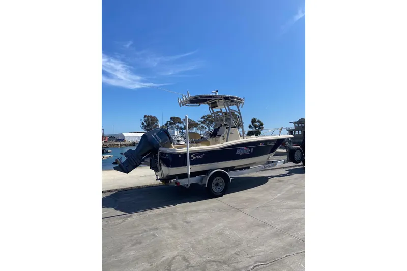 Slide: The Image of 2020 Scout 195 Sportfish boat on trailer at marina under clear blue sky. - 12