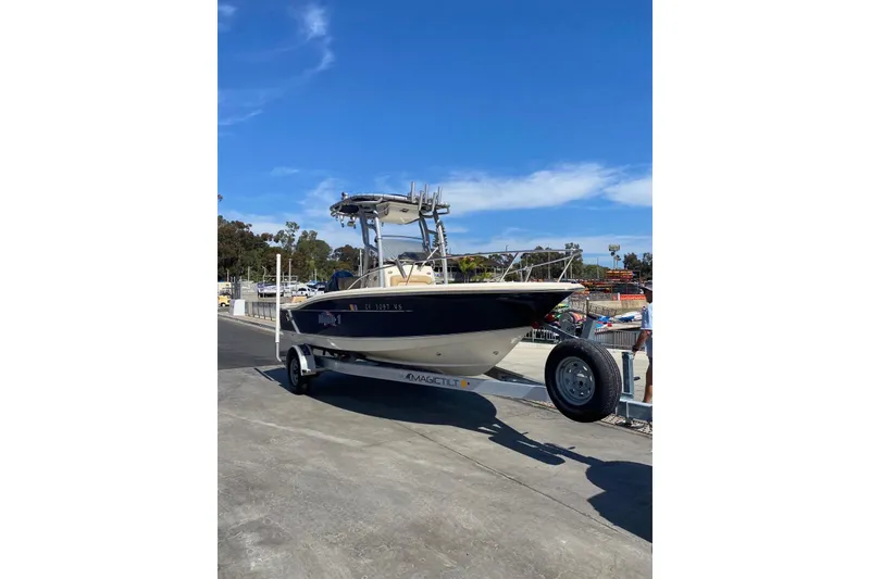 Slide: The Image of 2020 Scout 195 Sportfish boat on trailer under clear blue sky. - 13