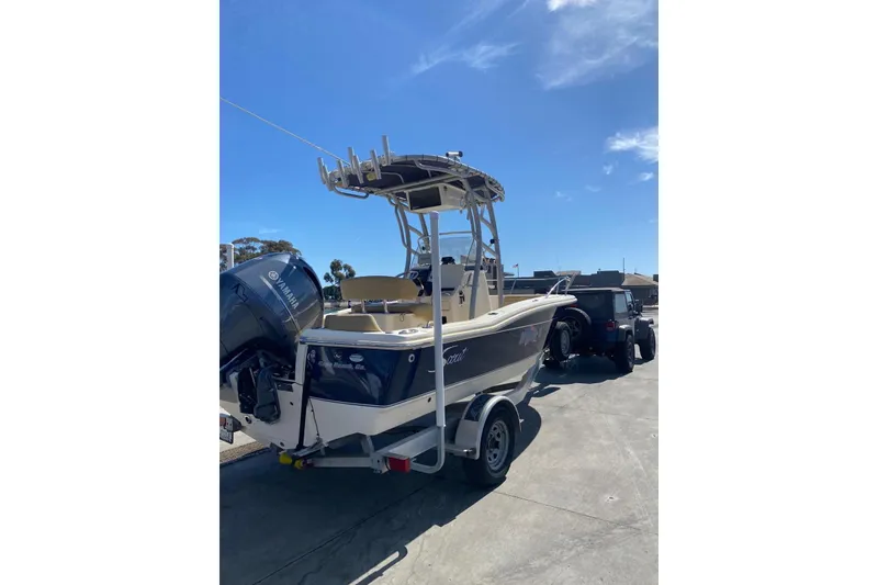 Slide: The Image of 2020 Scout 195 Sportfish boat on trailer, parked outdoors under clear blue sky. - 15