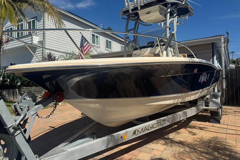 Slide: The Image of 2020 Scout 195 Sportfish boat on trailer, parked in driveway with American flag. - 23