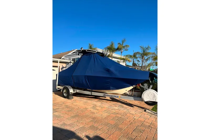 Slide: The Image of 2020 Scout 195 Sportfish boat covered, parked on a brick driveway under clear blue sky. - 37