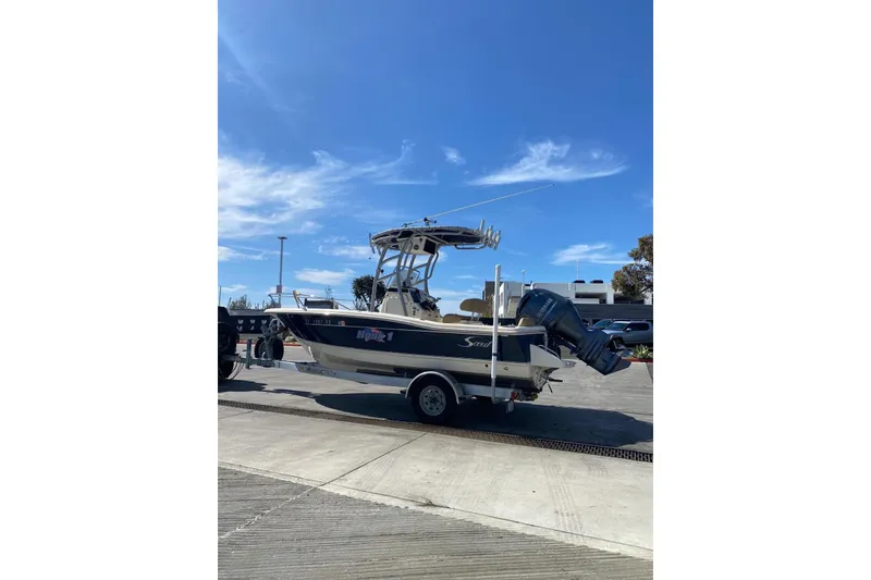 Slide: The Image of 2020 Scout 195 Sportfish boat on trailer under clear blue sky. - 7