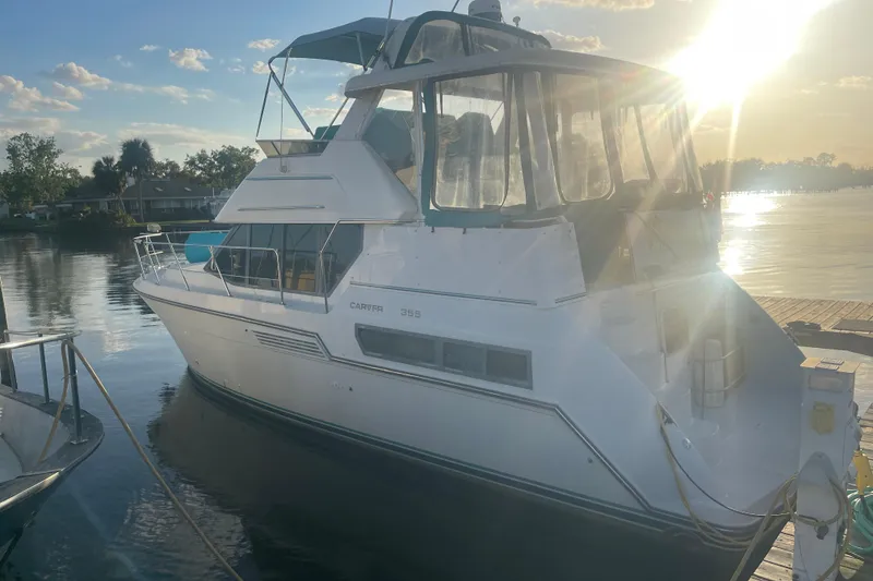 The Image of 1995 Carver 355 Aft Cabin Motor Yacht docked at sunset, reflecting on calm water. - 1