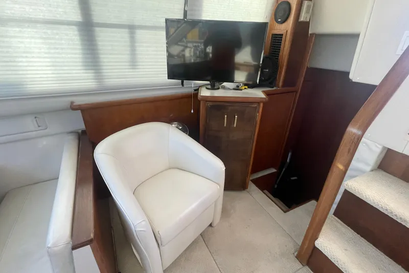 Slide: The Image of 1995 Carver 355 Aft Cabin Motor Yacht interior with chair, TV, and wooden cabinetry. - 17