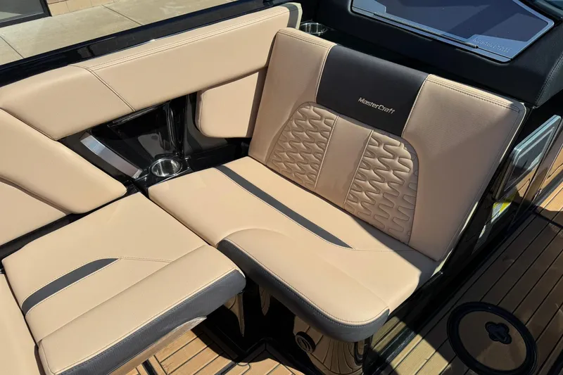Slide: The Image of 2022 MasterCraft X24 boat interior with beige and black seating, featuring stylish stitching. - 10
