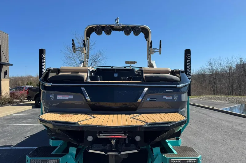 Slide: The Image of 2022 MasterCraft X24 boat rear view in parking lot under clear blue sky. - 4