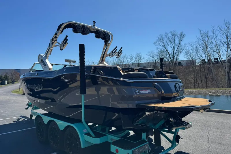 Slide: The Image of 2022 MasterCraft X24 boat on trailer, parked near a pond under clear blue sky. - 5