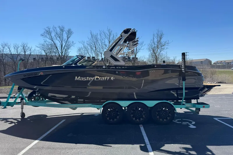 Slide: The Image of 2022 MasterCraft X24 boat on trailer in parking lot, clear sky background. - 6