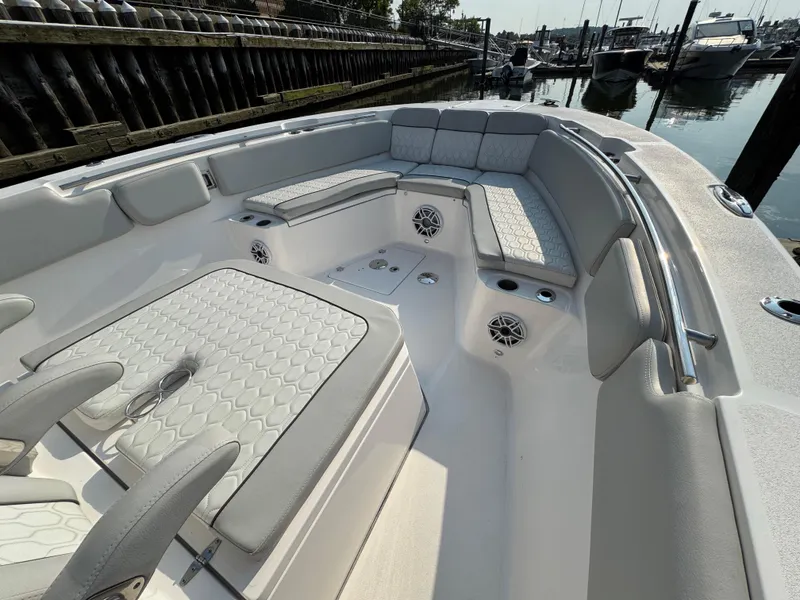 Slide: The Image of 2022 Sea Fox 328 Commander boat interior with cushioned seating and speakers in a marina. - 30