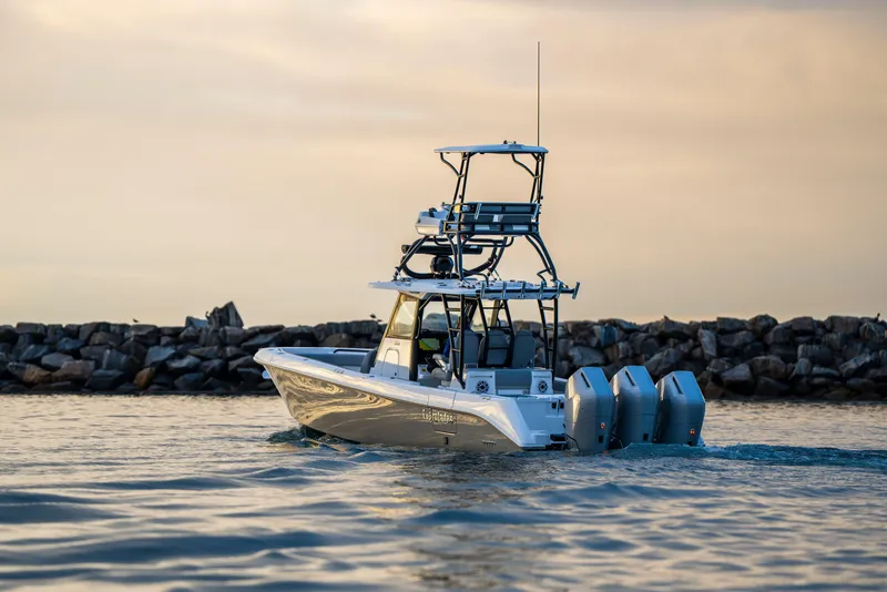 Slide: The Image of 2024 Everglades 365 Center Console boat cruising near rocky shoreline at sunset. - 12
