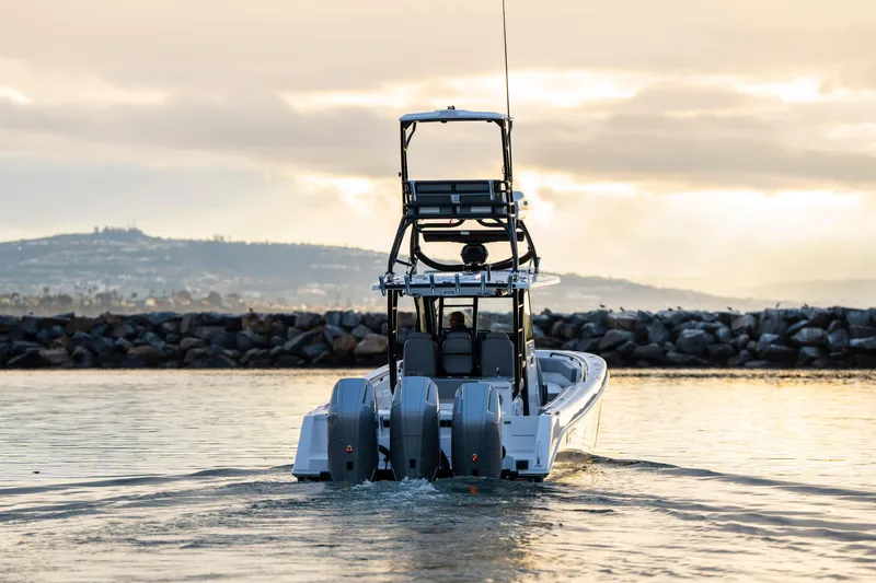 Slide: The Image of 2024 Everglades 365 Center Console boat cruising at sunset near rocky shoreline. - 28