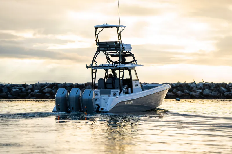 Slide: The Image of 2024 Everglades 365 Center Console boat cruising at sunset near rocky shoreline. - 3