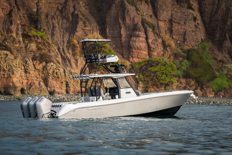 Slide: The Image of 2024 Everglades 365 Center Console boat cruising near rocky coastline. - 32