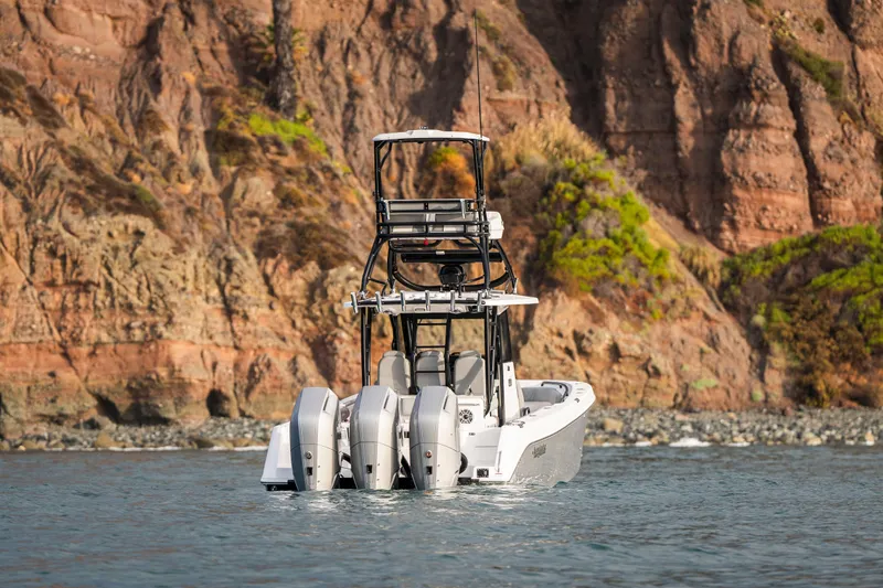 Slide: The Image of 2024 Everglades 365 Center Console boat with triple engines near rocky coastline. - 34