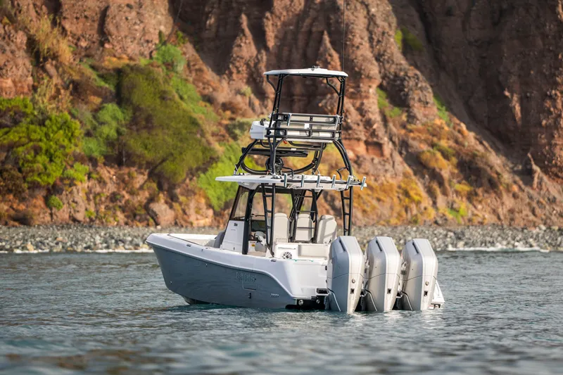 Slide: The Image of 2024 Everglades 365 Center Console boat with triple engines near rocky shoreline. - 35