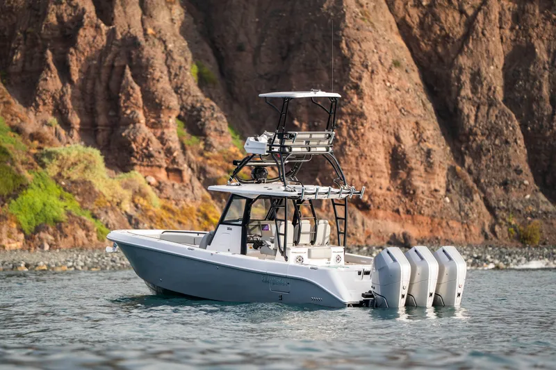 Slide: The Image of 2024 Everglades 365 Center Console boat with triple engines near rocky coastline. - 36